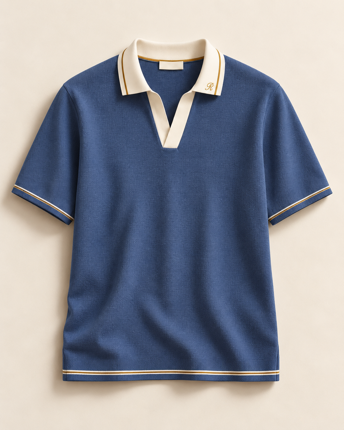 Lucrezia (S01), polo blu con collo chiaro, ricamo R e bordature dorate; capo intero con maniche e fondo visibili.